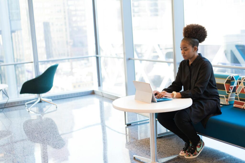 African American woman typing on a laptop in a bright, modern office space.